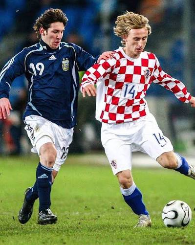 Young Lionel Messi in Argentina's navy away shirt challenging Luka Modrić of Croatia