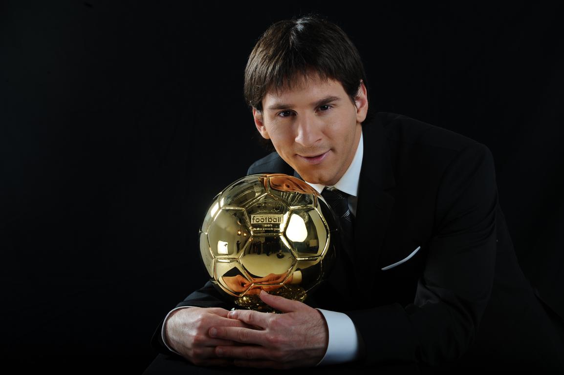 Lionel Messi in a dark suit posing with his first Ballon d'Or