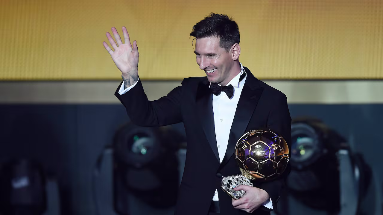 Lionel Messi waving while holding the Ballon d'Or