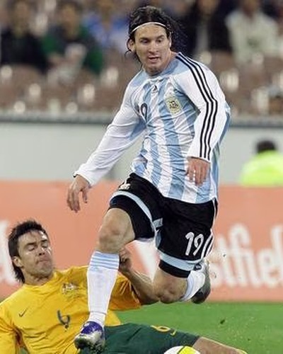 Lionel Messi in the Argentina shirt evading a sliding tackle from an Australian player at the MCG