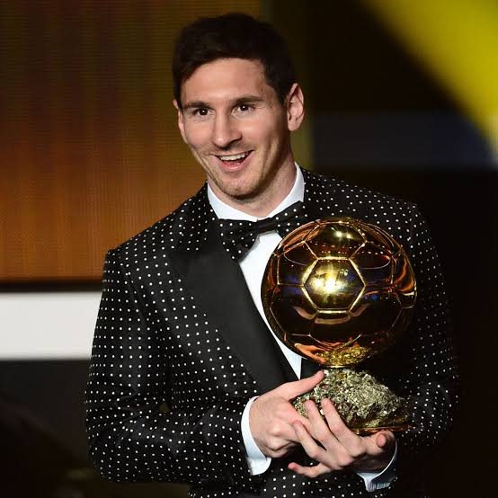 Lionel Messi in a polka dot suit holding the Ballon d'Or